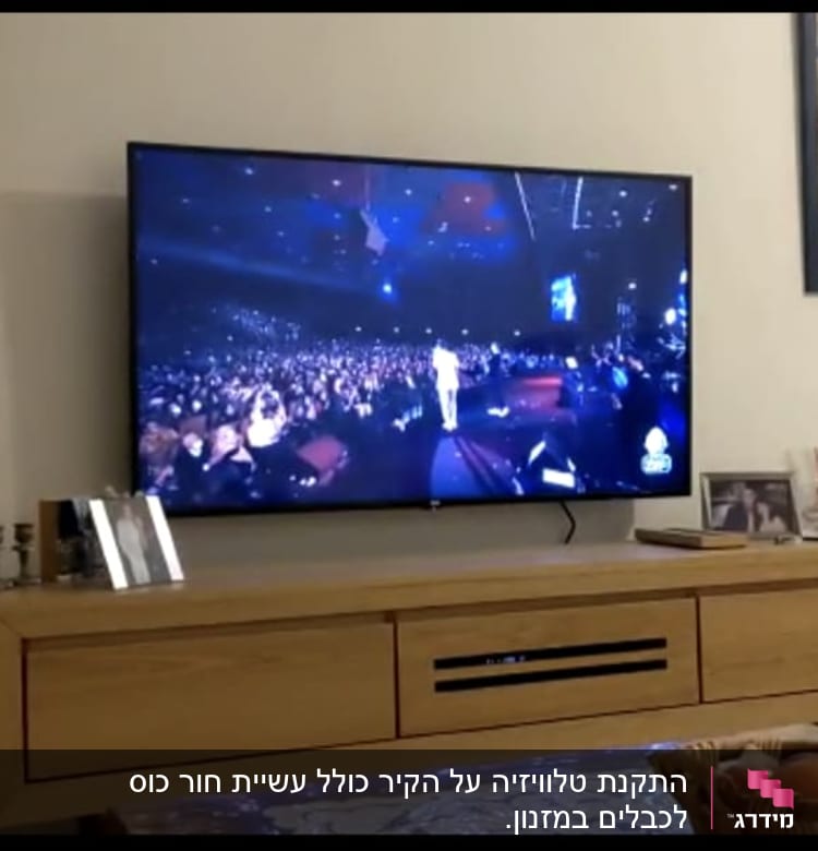 טלוויזיה תלויה על הקיר מעל שידה מעץ